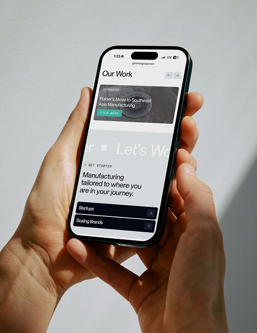 Hands holding a phone displaying the Genimex Group mobile website